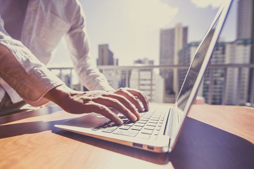 Foto: Laptop mit Hochhäusern im Hintergrund